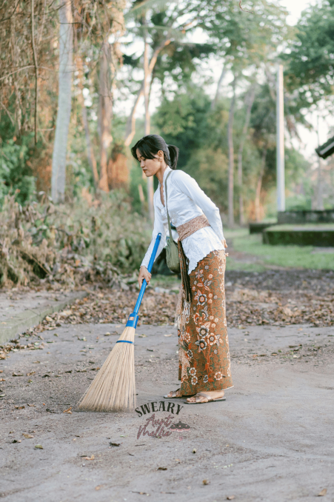 Spiritual housekeeping is also known as consecration. A woman in a light blue tunic top ceremonially sweeps to make ready for the first of her beginner witchcraft rituals.
