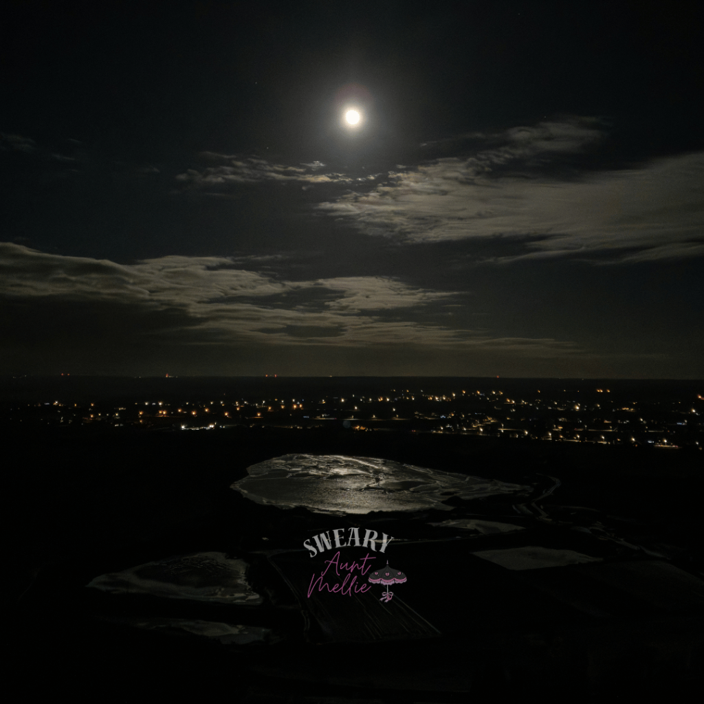 Pay attention to the world around you. Practice magic at home by noticing natural cycles. The moon shines brightly ablove a city scape and water.