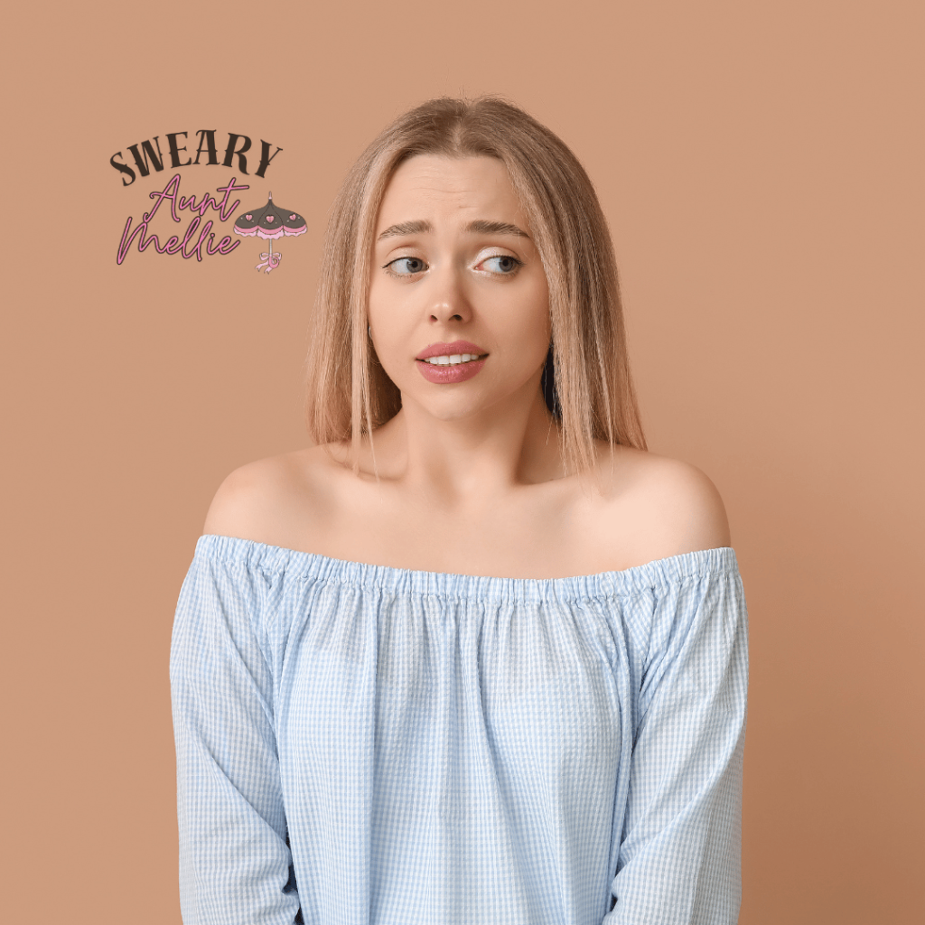 Crystal allies for your sex life can help you overcome shame. A young woman in a blue top shrinks in shame. She looks away, has an awkward facial expression, and has a shrunken posture.